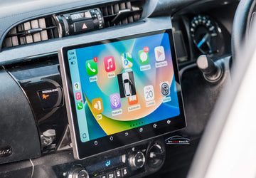 A 13.3 inch touchscreen car stereo system installed in a vehicle's dashboard, displaying a colorful interface with icons for Apple Carplay and Android Auto features.