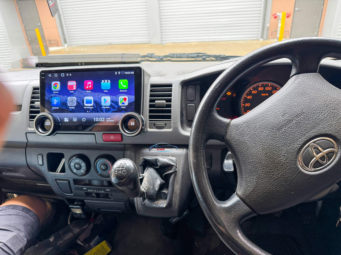 A 10.1-inch motor vehicle A/V player with dual knob control installed in a vehicle's dashboard, featuring a touchscreen interface displaying icons for Apple CarPlay and Android Auto.