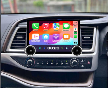 A 10 touchscreen car audio and vehicle information system installed in a vehicle's dashboard, displaying a colorful interface with icons for Apple CarPlay and Android Auto features.