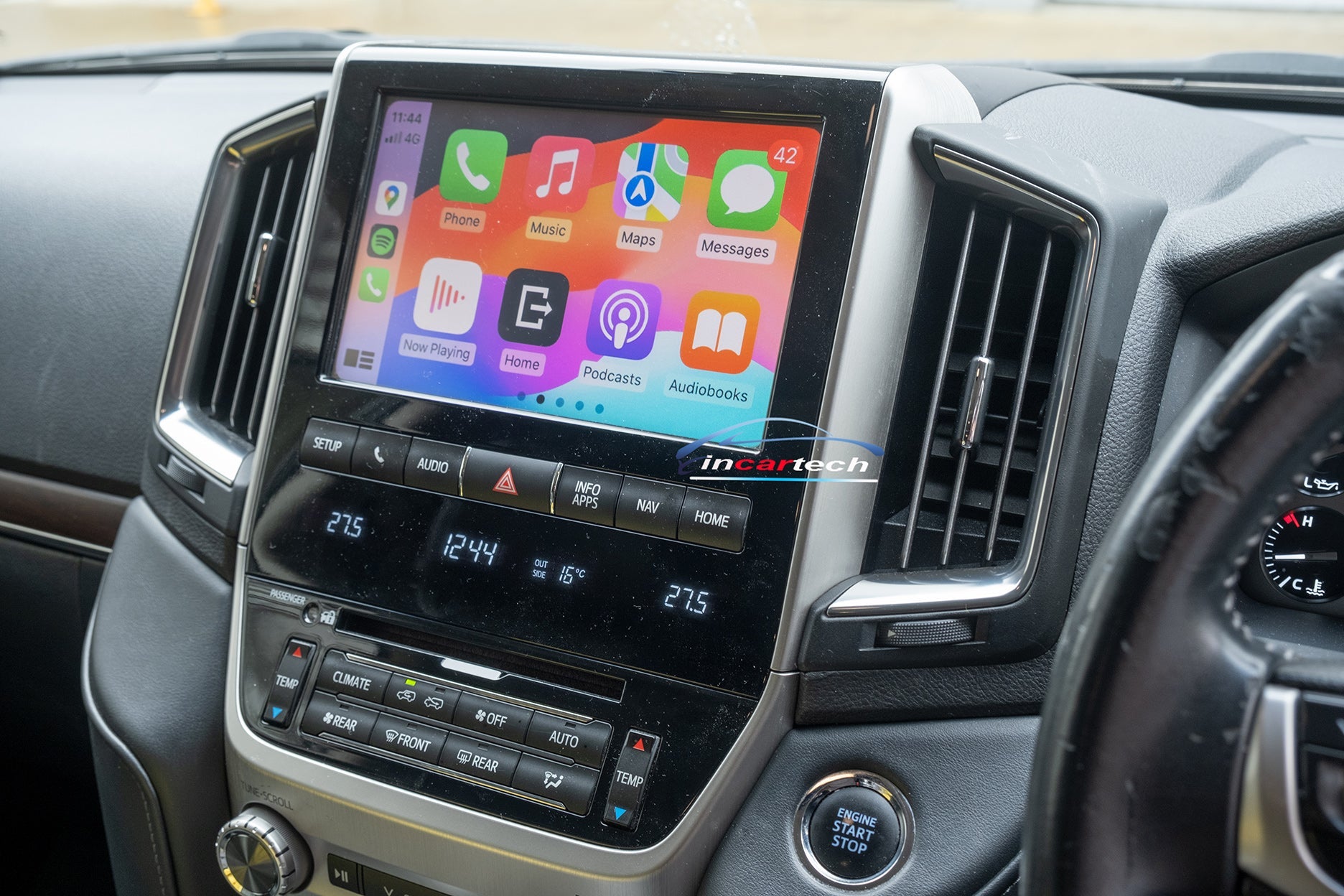 An aftermarket touch screen interface module for a Toyota Land Cruiser vehicle, displaying a colorful car audio and navigation interface.