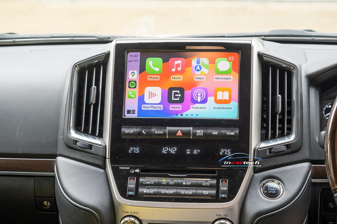 An aftermarket touch screen interface module for a Toyota Land Cruiser vehicle, displaying a colorful car audio and navigation interface.