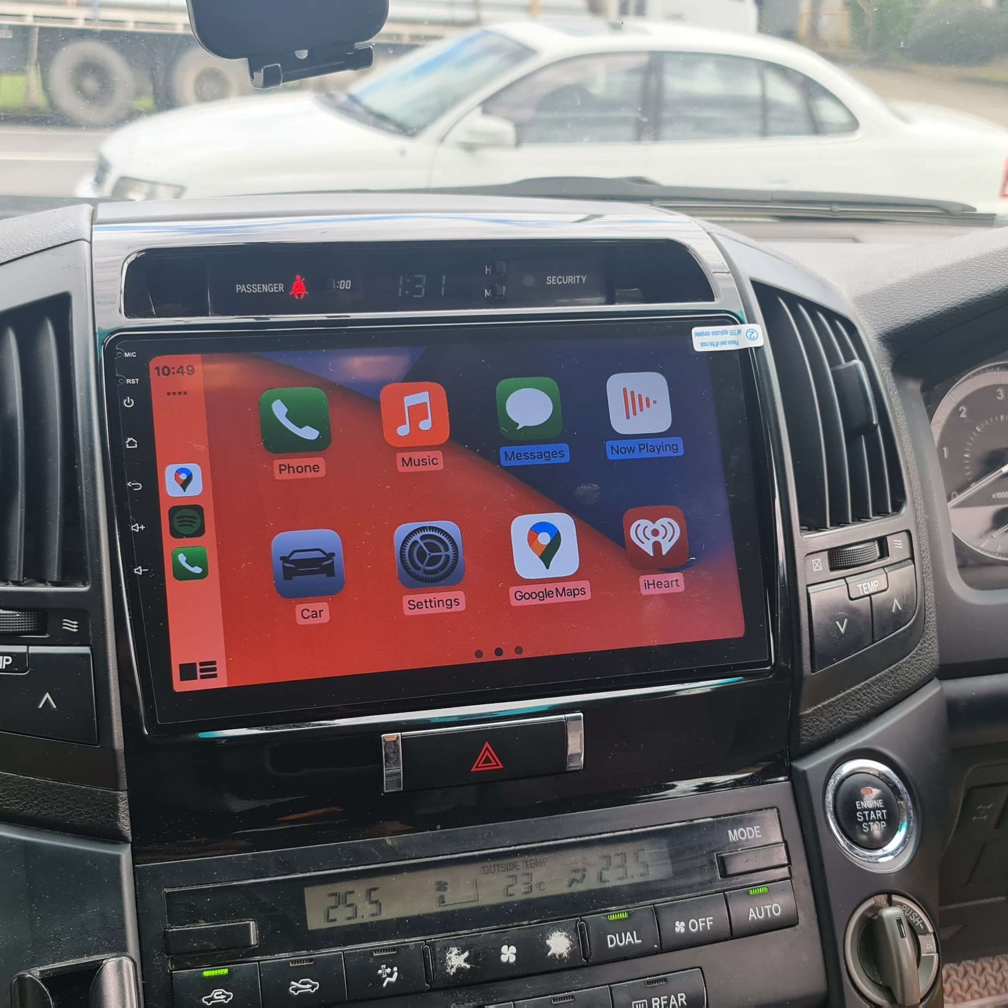 An aftermarket touch screen car stereo system displayed inside a vehicle's dashboard, featuring icons for Apple CarPlay and Android Auto.