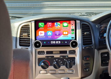 An aftermarket touch screen car stereo system interface displayed inside a vehicle's dashboard. The interface shows a colorful screen with various icons for Apple CarPlay and Android Auto features.