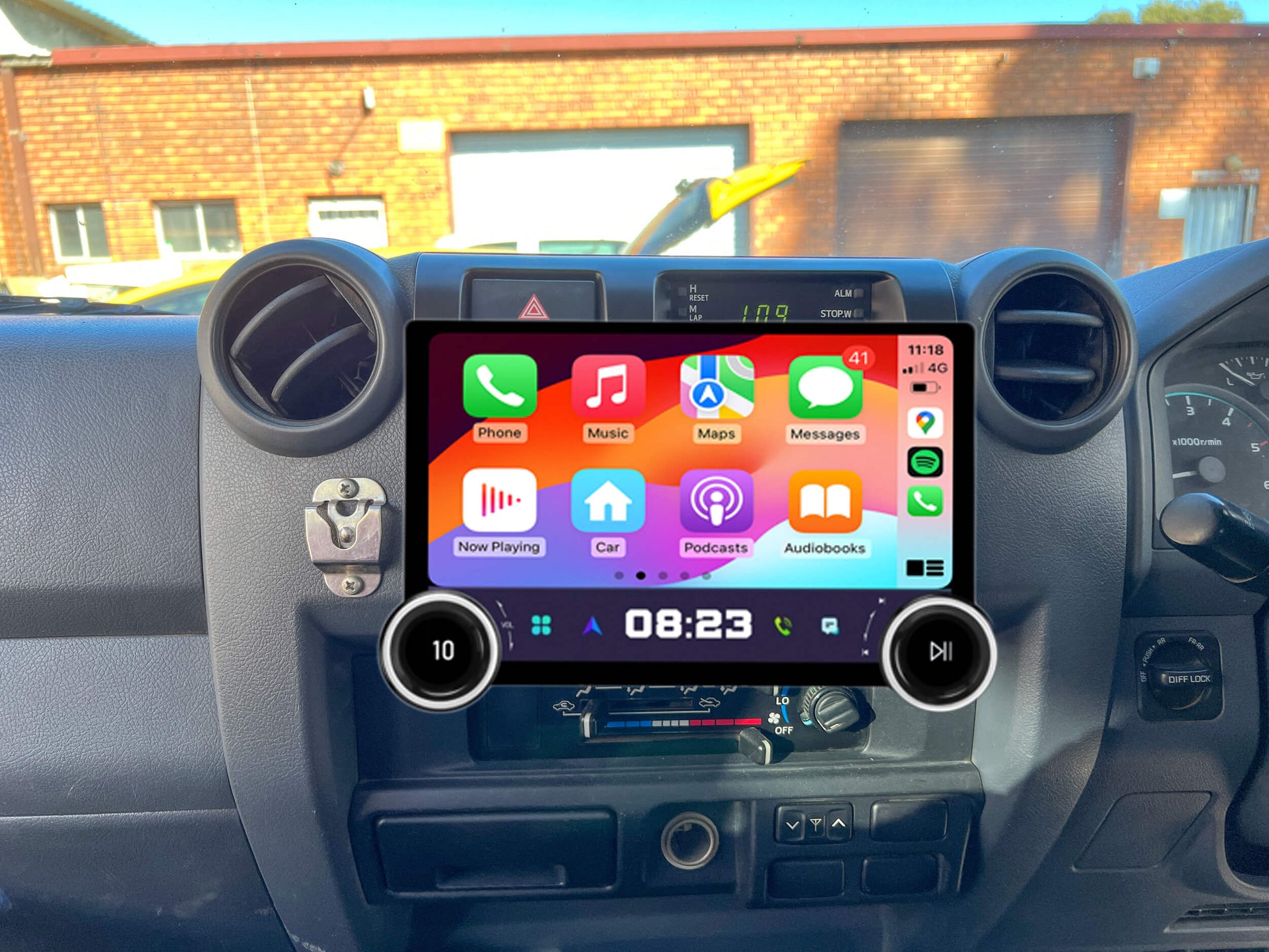 An aftermarket car stereo radio with a touchscreen interface installed in a vehicle's dashboard. The screen displays various icons for audio, navigation, and smartphone integration.