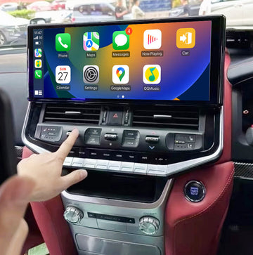 A hand touching a touchscreen in a vehicle's dashboard, which features a navigation interface with Apple CarPlay and Android Auto icons.