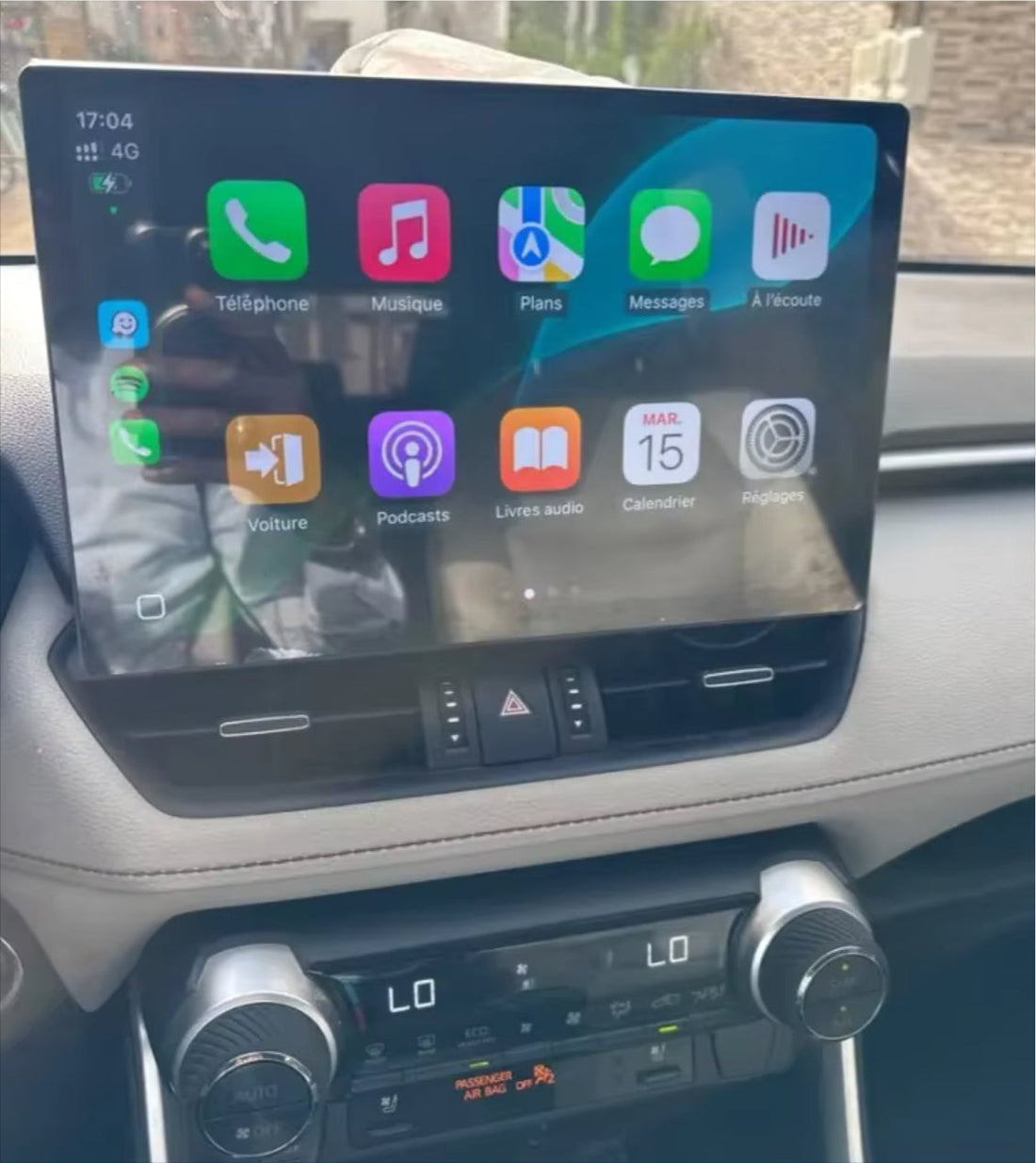 A touchscreen car stereo system installed in a vehicle's dashboard, displaying a colorful interface with icons for Apple CarPlay and Android Auto features.
